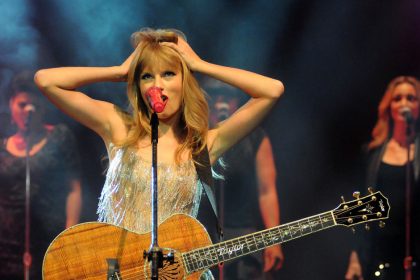 Taylor Swift holds her head in her hands on stage