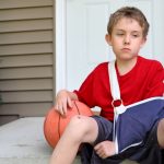 Boy sits on step with arm injury