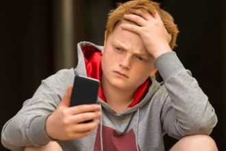 Teenage boy looks sad using his phone