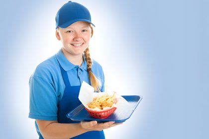 Fast food worker in uniform holds a bowl of chips