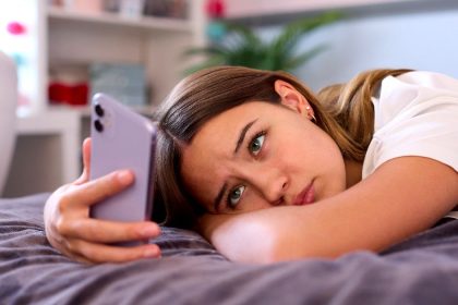 Teen girl uses Instagram on phone while laying on a bed