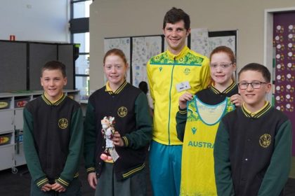 Olympic athlete standing with school students