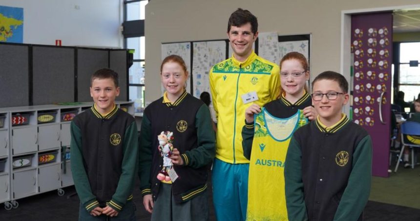 Olympic athlete standing with school students