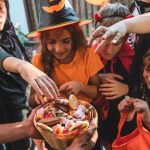 Kids at Halloween collect candy from a bowl