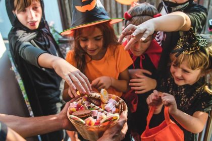 Kids at Halloween collect candy from a bowl