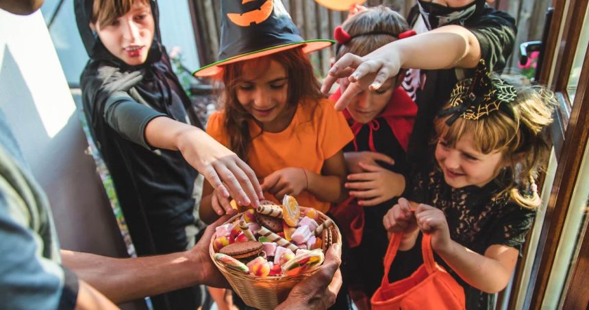 Kids at Halloween collect candy from a bowl